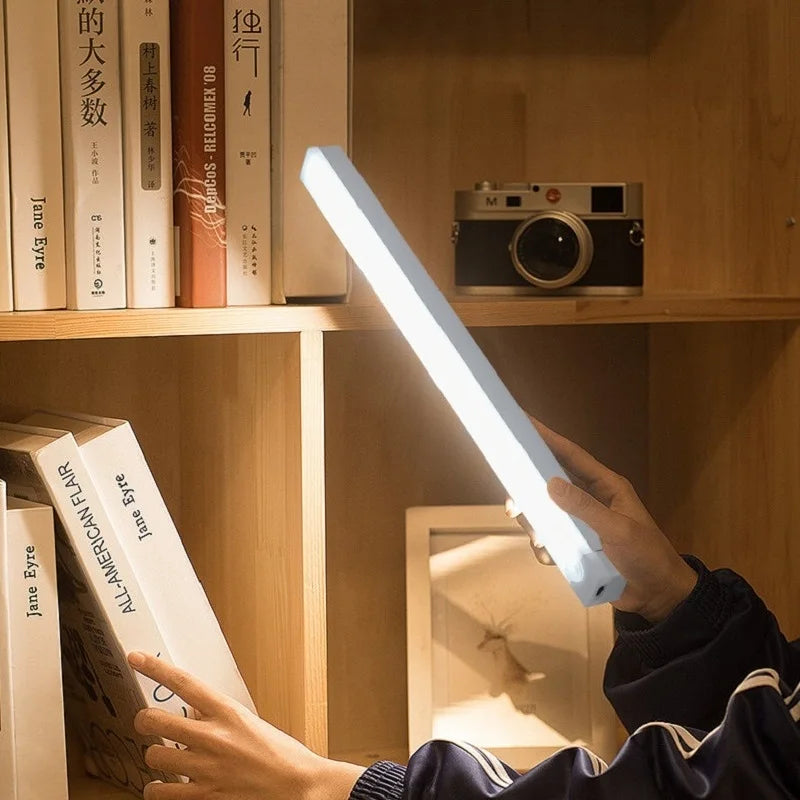 Réglette LED tenue à la main devant une bibliothèque